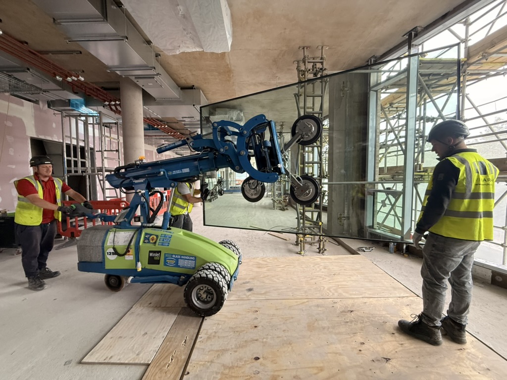 Delta Facades installers using a Winlet glass lifter to position a curtain wall panel during benchmark installation
